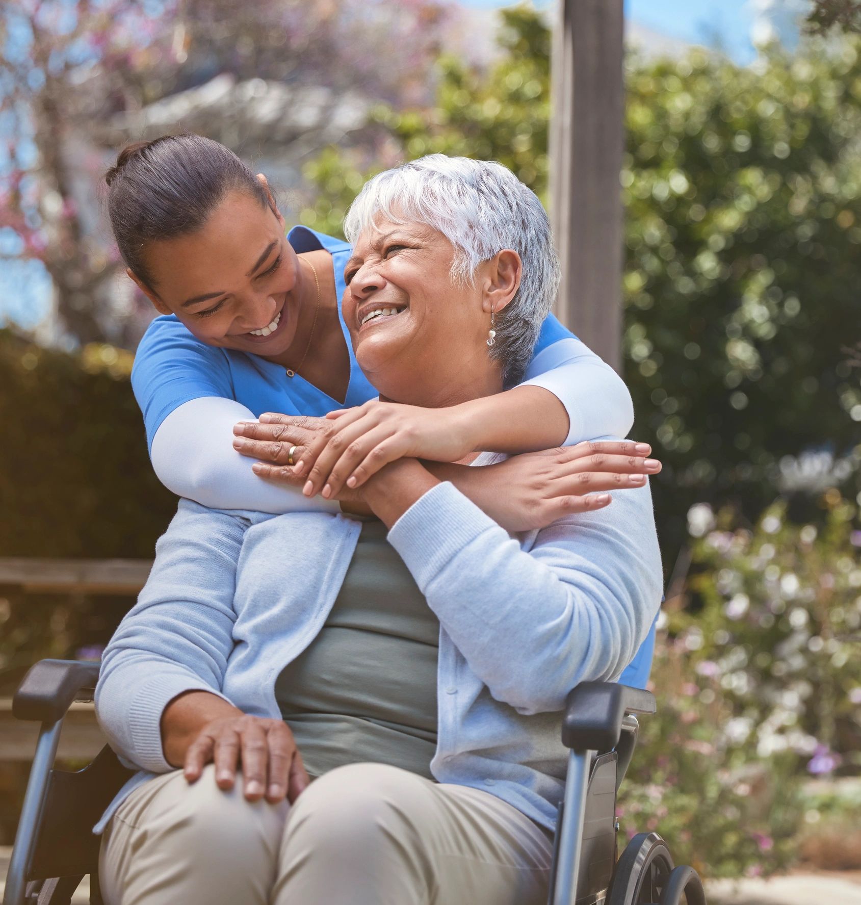 Caregiver supporting a senior in a wheelchair outdoors