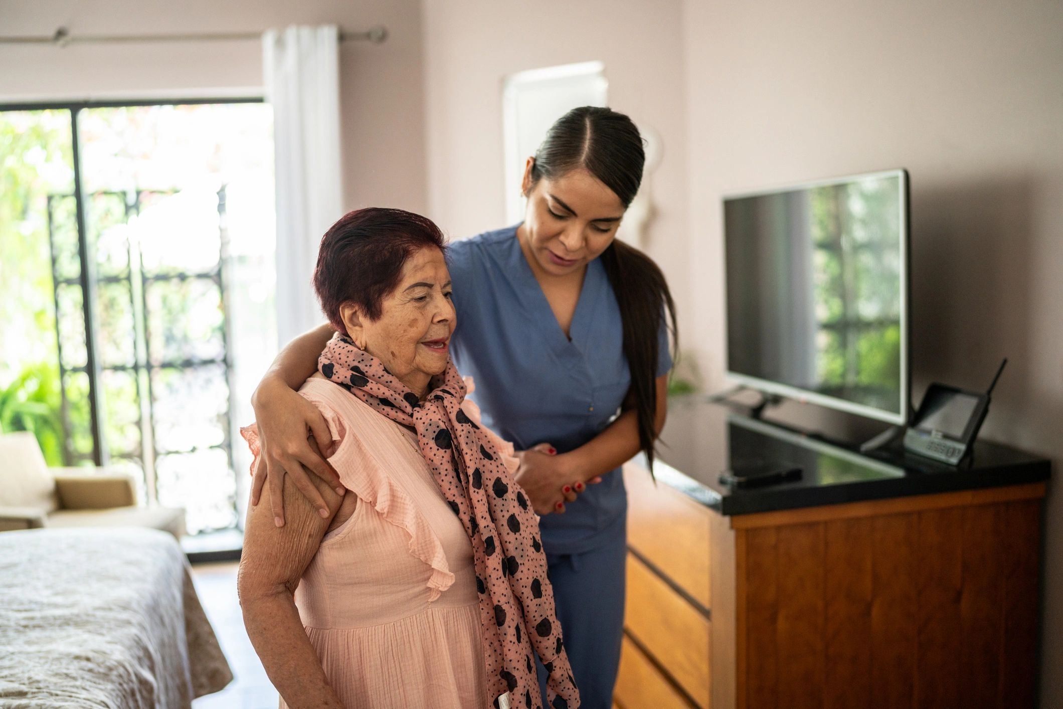 Home caregiver assisting a senior woman while walking